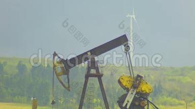 背景为灰色天空的油井抽油机和风力发电厂